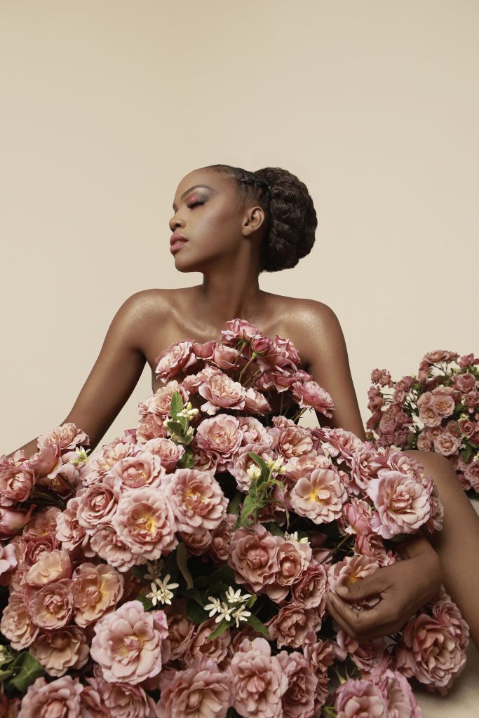 Striking image of beautiful woman draped in large open dusty pink garden roses.