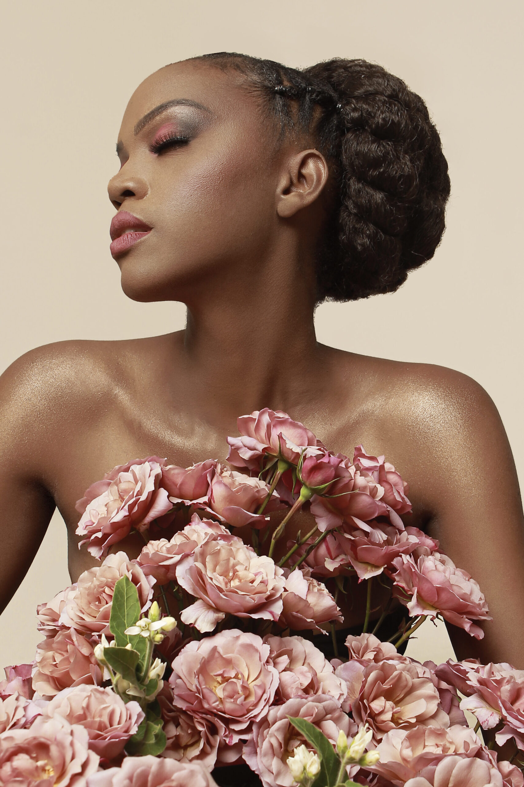 Striking image of beautiful woman draped in large open dusty pink garden roses. 