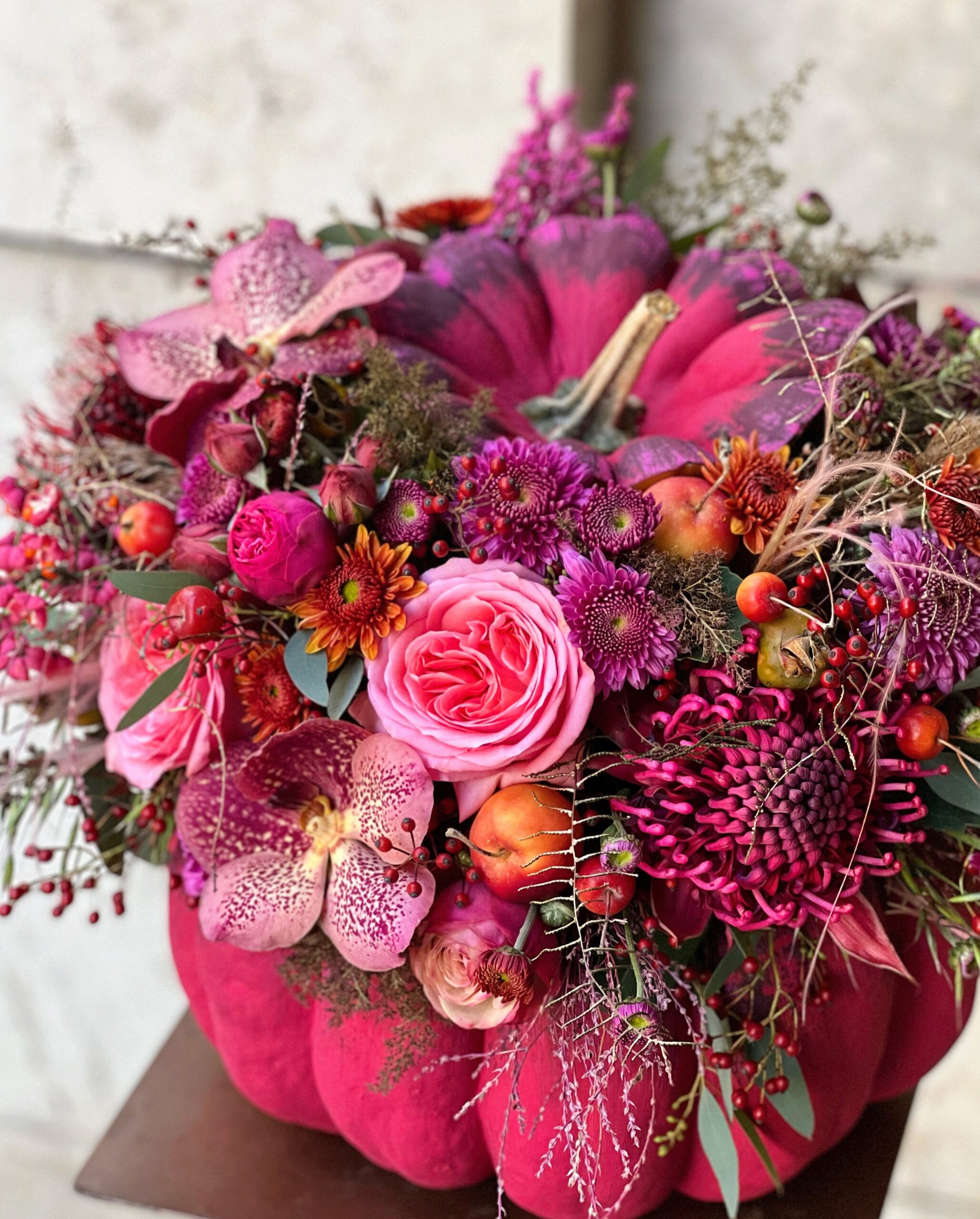 Pink pumpkin vase flower arrangement with garden roses, orchids, autumn berries and seasonal flowers, designed by Attila Nemeth.